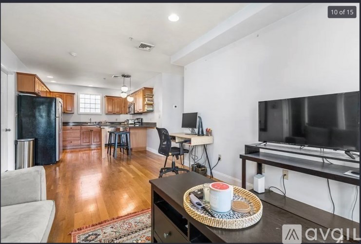 A kitchen with a refrigerator, a dining table, and a television.