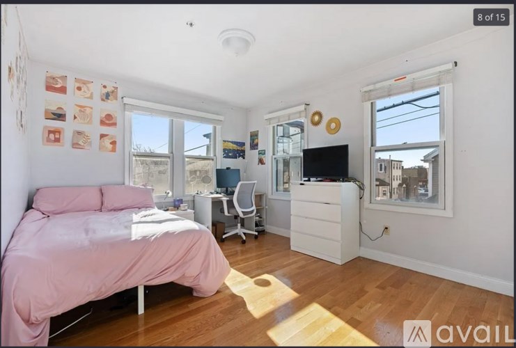A bedroom with a pink bed and a window overlooking a cityscape.