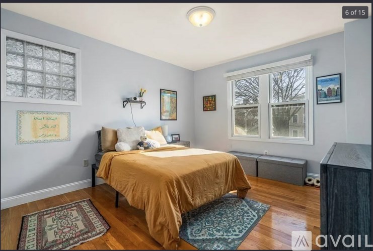 A bedroom with a bed, a window, and a rug on the floor.