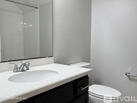 A white sink in a bathroom with a toilet and a mirror.