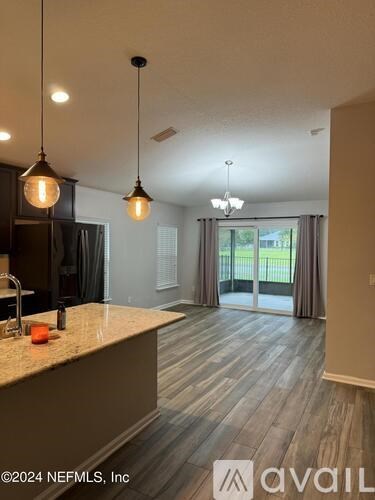 A kitchen with a marble countertop and pendant lights.