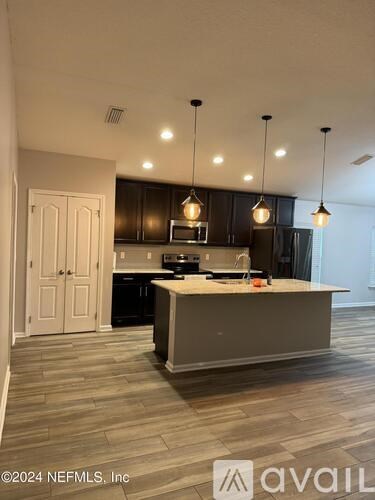 A modern kitchen with a large island and pendant lights.