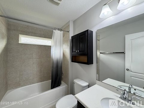 A bathroom with a white tub, sink, and toilet.