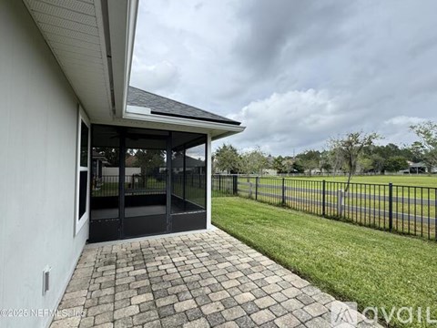 A patio area with a black fence and a glass door leading to a backyard.