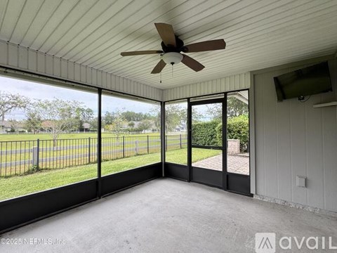 A room with a ceiling fan and sliding glass doors leading to a backyard.