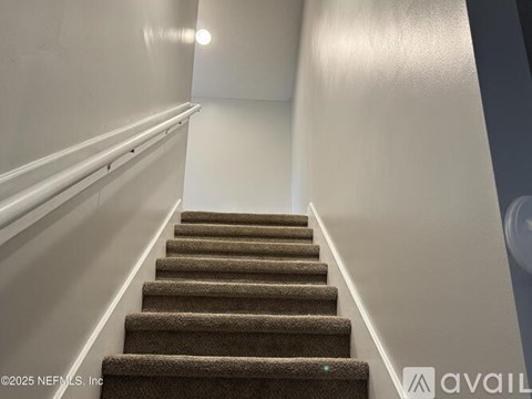 A staircase with a carpeted runner and white walls.