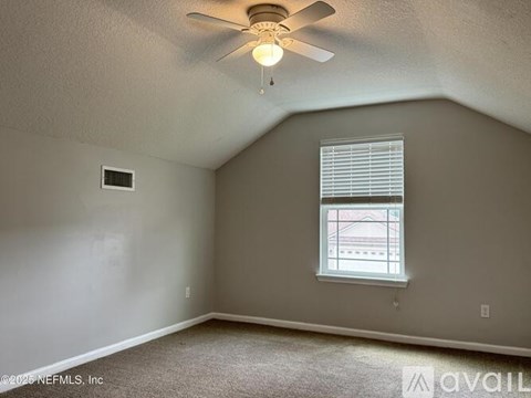 A room with a ceiling fan and a window with blinds.
