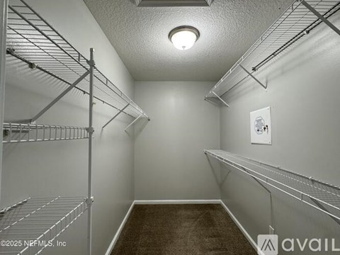 A walk-in closet with shelving and a carpeted floor.