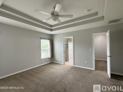 A spacious room with a ceiling fan and carpeted floor.