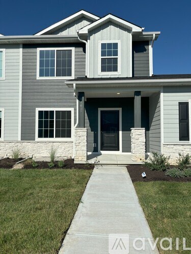 A house with a grey and white exterior and a stone pillar on the front porch.