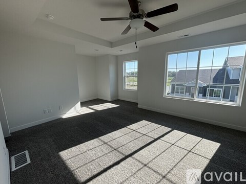 A spacious room with a ceiling fan and large windows.