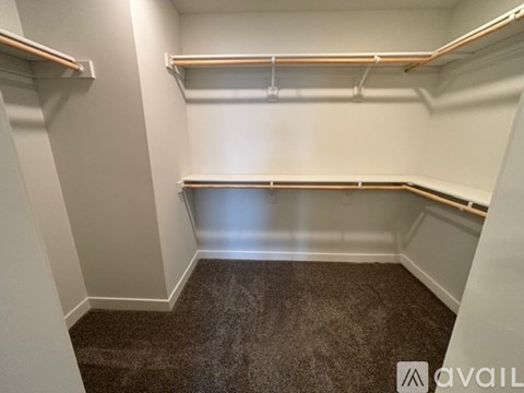 A small, empty room with a carpeted floor and two metal shelves.