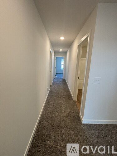 A long hallway with a carpeted floor and white walls.