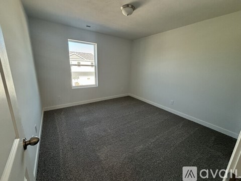 A room with a carpeted floor and a window showing a view of a house.