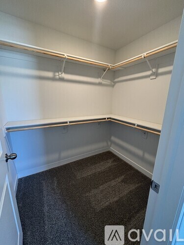 A carpeted room with a door and a wall with hooks.