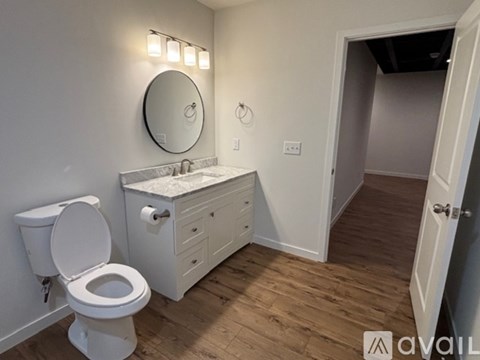 A bathroom with a toilet, sink, and mirror.