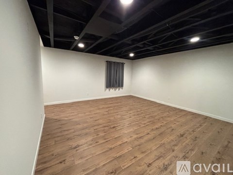 A room with wooden flooring and a window with curtains.