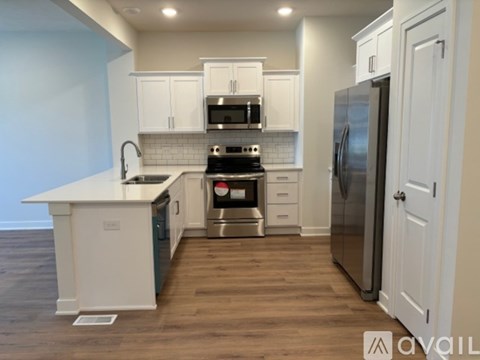 A kitchen with white cabinets and a stainless steel refrigerator.