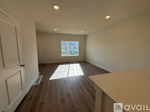 A room with wooden floors and a window showing a street view.