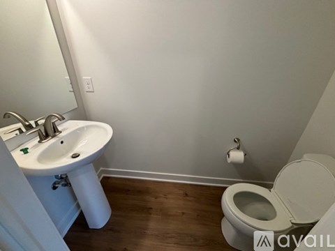 A white toilet is in a bathroom with a white sink.