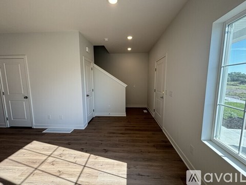 A room with wooden floors and white walls, with a window on the right side.