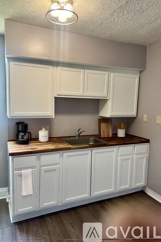 A kitchen with white cabinets and a wooden countertop.