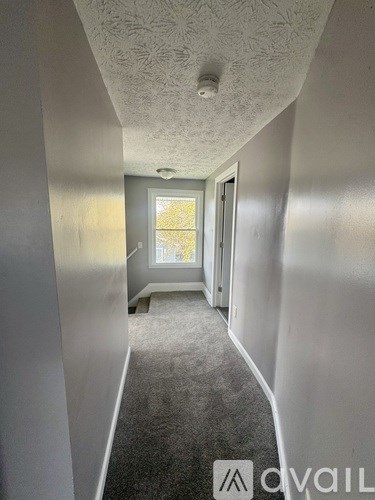 A long hallway with a carpeted floor and a door at the end.