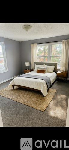A bedroom with a large bed and a window with curtains.
