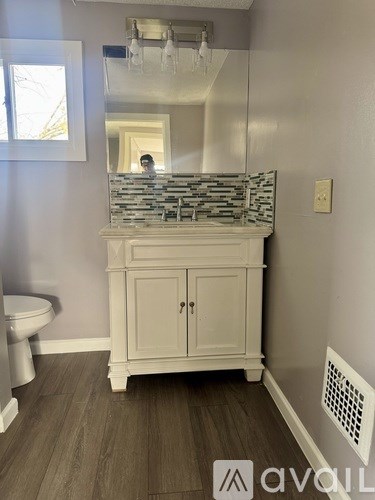 A bathroom with a toilet, a sink and a mirror.
