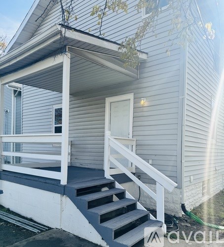 A white porch with a staircase leading to a door.