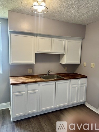A kitchen with white cabinets and a wooden countertop.