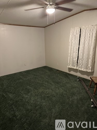A room with a carpeted floor and a window with curtains.