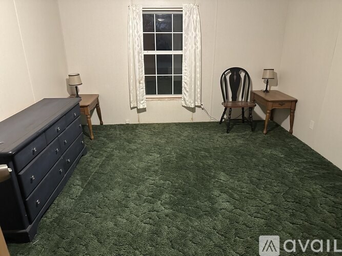 A room with a bed, desk, chair, and window.