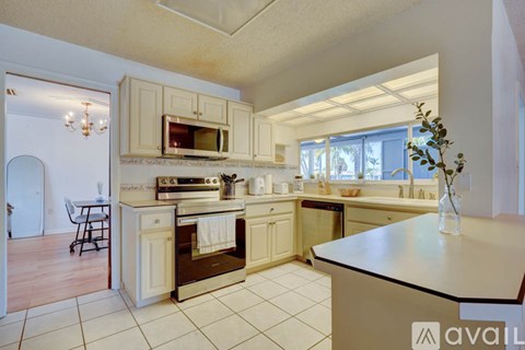 A kitchen with a white counter top and a microwave on the counter.