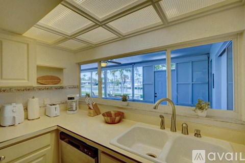 A kitchen with a white sink and a window with blue curtains.