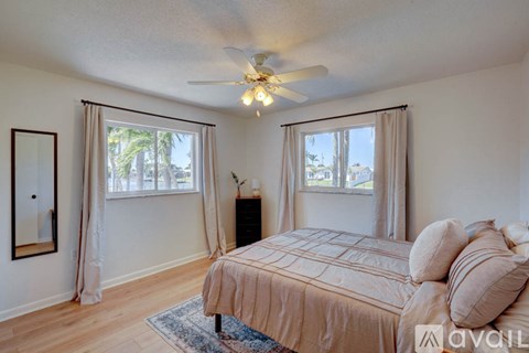 A bedroom with a bed, a ceiling fan, and a window with curtains.