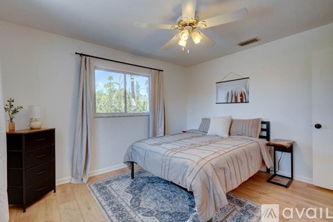 A bedroom with a bed, a dresser, and a ceiling fan.