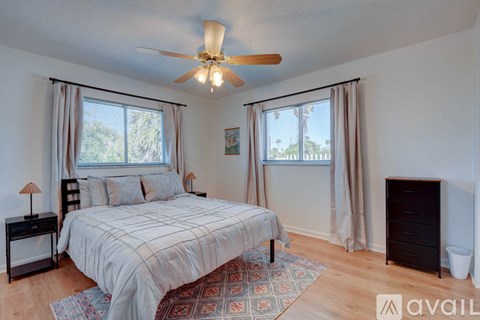 A bedroom with a bed, dresser, and ceiling fan.