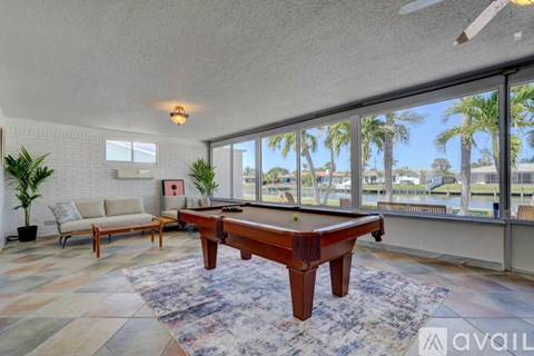 A pool table is in the middle of a room with a couch and a plant.