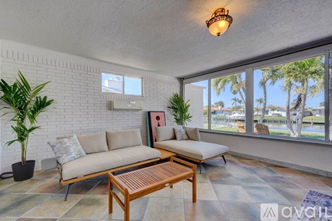 A living room with a white brick wall and a large window overlooking a beach.