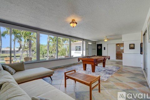 A living room with a couch, coffee table, and a pool table.