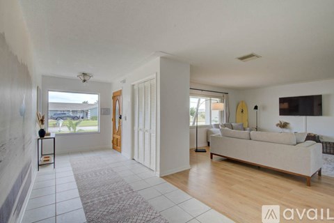 A spacious living room with a white sofa and a large window.