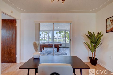 A dining room with a table, chairs, and a potted plant.