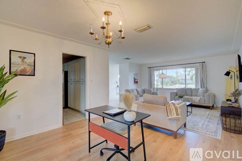 A living room with a black coffee table and a chandelier hanging from the ceiling.