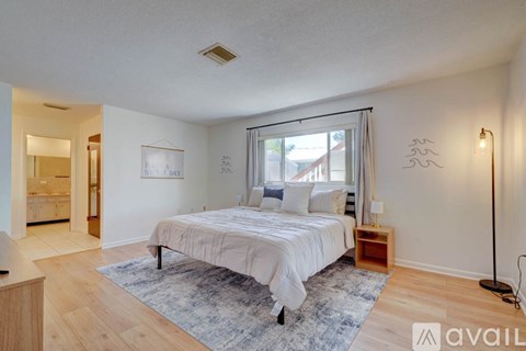 A bedroom with a large bed and a window with curtains.