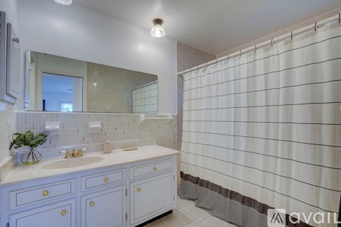 A bathroom with a white sink and a white shower curtain.
