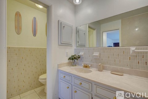 A bathroom with a toilet, sink, and mirror.