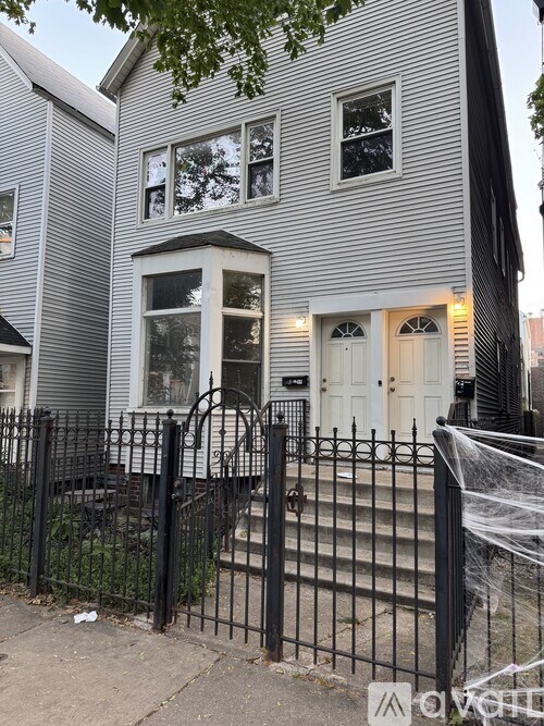 A grey house with a black fence in front.