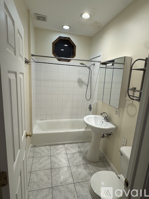 A bathroom with a white tub, sink, and toilet.