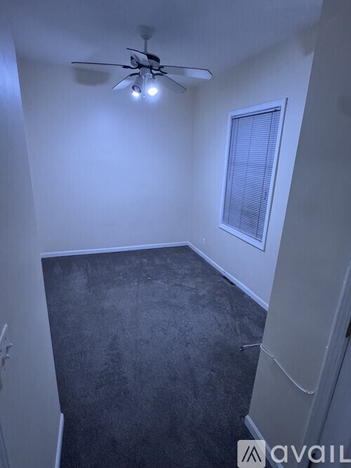 A room with a ceiling fan and a window with blinds.
